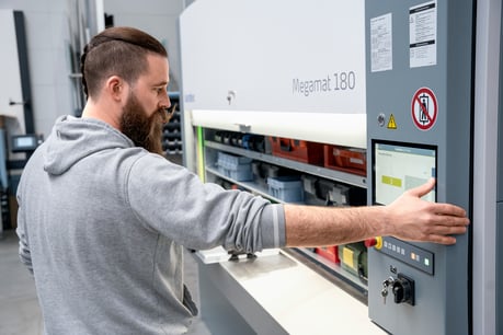 Mitarbeiter bedient einen Kardex Megamat Essential mit Touchscreen in einem modernen Lager- und Arbeitsbereich.