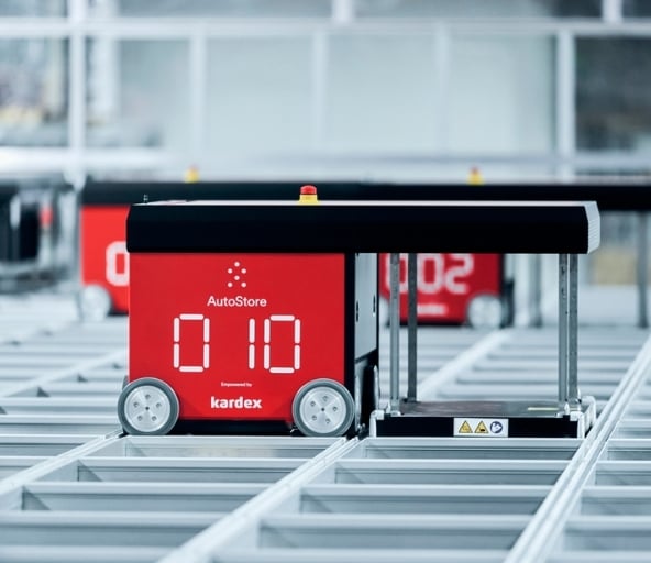 Red AutoStore robot digging into grid to retrieve inventory bin